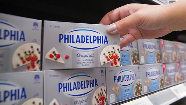 Hand grabbing Philadelphia packaging on store shelf.