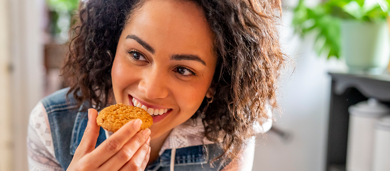Woman smiling while taking a bite of Belvita biscuit.